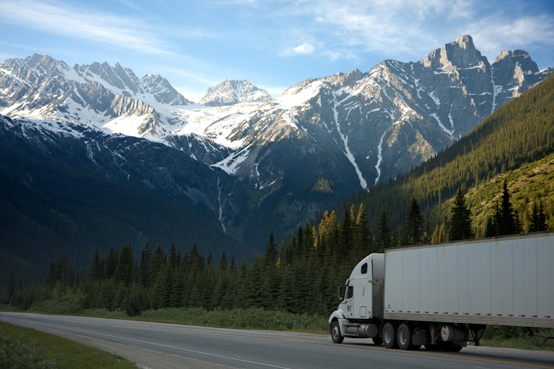 White semi truck hauling freight on a mountain highway in the United States